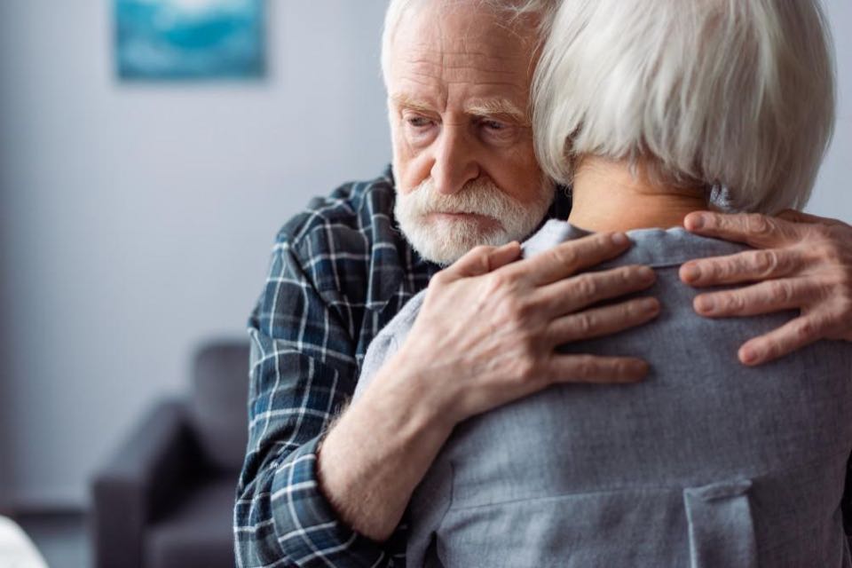 A partner sitting close in a softly lit room, listening as a loved one talks.