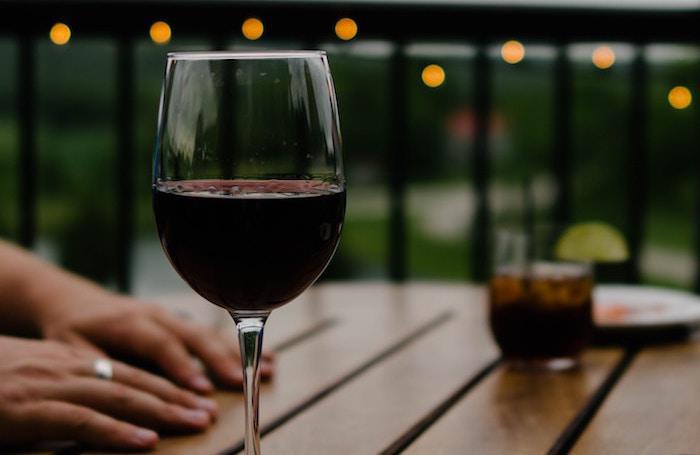 A wine glass on a table at dusk, illustrating quiet, repeated drinking at home.